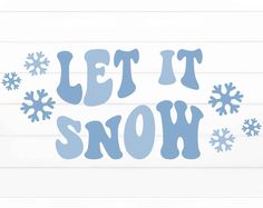 the words let it snow are shown in blue on a white wood planked wall