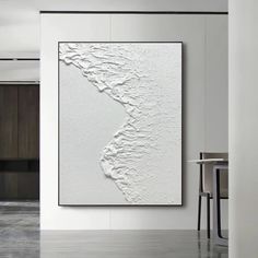 a large white painting hanging on the wall next to a dining room table and chairs