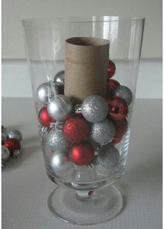 a glass vase filled with ornaments and a roll of paper sticking out of the top