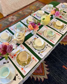 a table set up with playing cards, cups and saucers on top of it