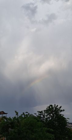 there is a rainbow in the sky over some trees