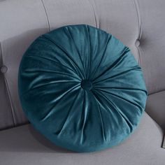 a blue round pillow sitting on top of a gray couch