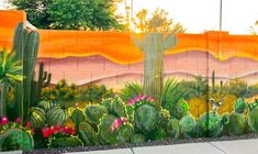 a mural painted on the side of a building with cactus and mountains in the background