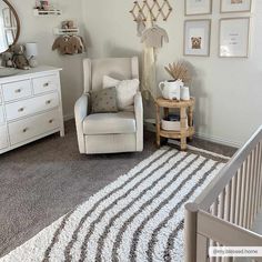 a baby's room with a chair, dresser and pictures on the wall above it