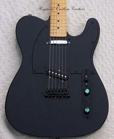 a black electric guitar laying on top of a white sheet with the strings still attached