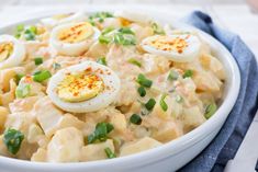 a bowl filled with macaroni salad topped with hard boiled eggs and green onions