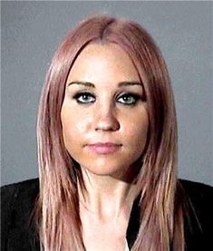 a woman with long pink hair wearing a black blazer and white shirt is looking at the camera