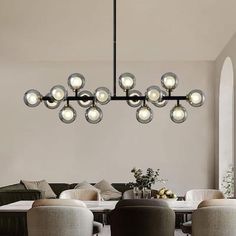 a modern chandelier hangs over a dining room table with chairs and couches