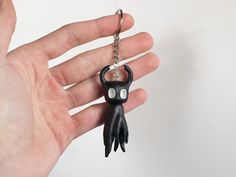 a hand holding a black keychain with white eyes