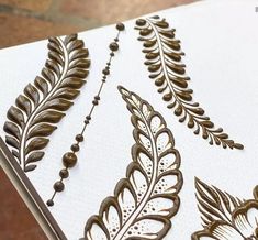 an intricately designed piece of paper with leaves and beads on it's edges