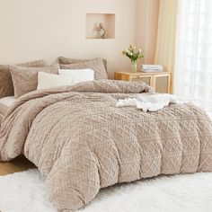 a bed in a bedroom with beige comforter and pillows