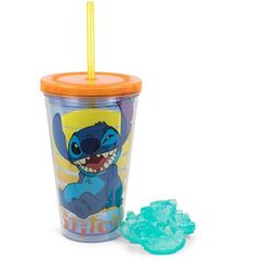 a plastic cup with an orange lid and straw in front of it next to blue gummy bears