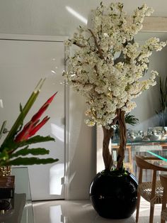 a vase filled with white flowers sitting on top of a table next to a mirror