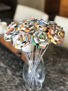 a vase filled with lots of paper flowers on top of a marble countertop next to a white chair