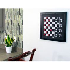 a black and white checkerboard wall hanging above a kitchen counter with a potted plant