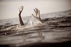 two hands reaching up out of the water to catch a frisbee in the air