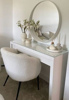 a white chair sitting in front of a desk with a mirror on top of it