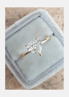 an engagement ring with a pear shaped diamond in it on a velvet box that is sitting on a marble surface