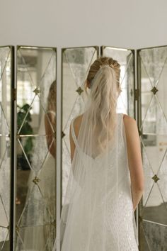 the back of a bride's dress as she stands in front of a mirror