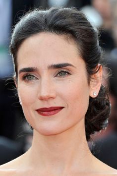 a woman with dark hair and green eyes wearing a red lipstick on the red carpet