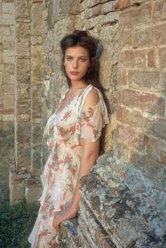 a woman leaning against a stone wall