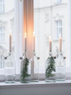 three glass bottles with candles in them sitting on a window sill