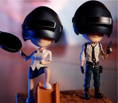 two figurines are standing next to each other with helmets on their heads and one is holding a frying pan