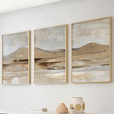 three paintings hang on the wall above a table