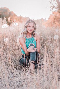 a woman sitting in tall grass with her legs crossed