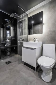 a white toilet sitting next to a sink in a bathroom under a mirror and shower