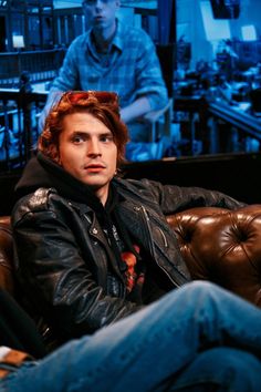 a man sitting on top of a brown leather couch