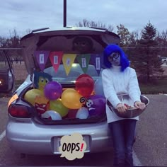 a woman sitting in the back of a silver car with balloons and decorations on it