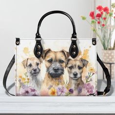 a handbag with two dogs on it and flowers in the background, sitting on a table