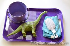 a toy dinosaur with a toothbrush on a purple tray