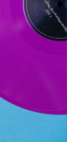 a purple vinyl record sitting on top of a blue surface