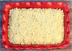 an uncooked casserole in a red dish on top of a wooden table