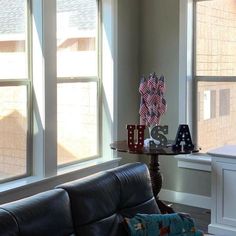 a living room filled with furniture next to two large windows covered in shades of red, white and blue