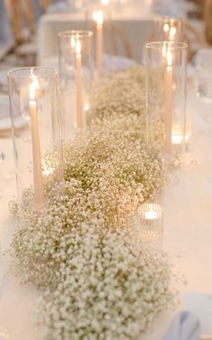 the table is set with candles and baby's breath centerpieces on it