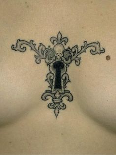 the back of a woman's breast with an ornate key tattoo on her chest