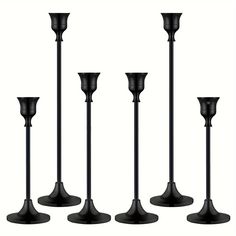 four black candlesticks are lined up against a white background