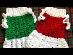 two crocheted christmas sweaters sitting on top of a plaid tablecloth with red, white and green colors