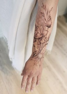 a woman's arm with flowers and leaves tattooed on the left side of her arm