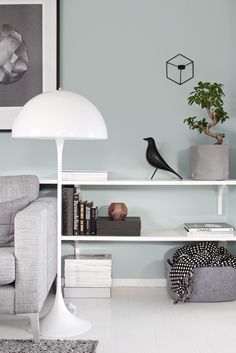 a living room filled with furniture and a white lamp on top of a book shelf