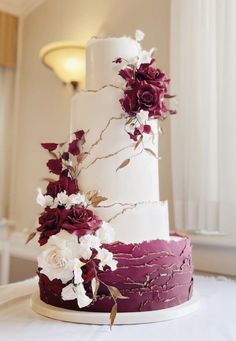 a three tiered wedding cake with red and white flowers