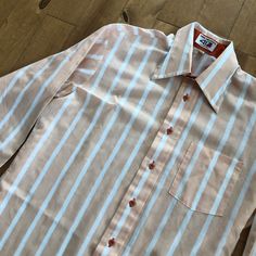 "This piece is a vintage men's long sleeve button up shirt from the 1980s made by Van Heusen. This peach and white striped shirt has a straight collar, a single patch pocket on the front and dark orange contrasting buttons. -Van Heusen -Stamped on the front hem by manufacturer Tag Size: N/A, fits like a large *refer to measurements for true fit* Pit to Pit: 23\" Length: 29\" Please also assess the photos and measurements carefully using your own personal judgement as we do not accept returns. Keep in mind that this is a piece of vintage clothing that may hold a residual scent from its past. While we wash all of the clothing we sell (except for certain items which are steam cleaned) we cannot guarantee that we have been able to remove all of the stubborn scents. Buyers should be prepared fo Vintage Summer Shirt With Button Cuffs, Retro White Long Sleeve Shirt, Retro Long Sleeve Shirt With Button Cuffs, Vintage Long Sleeve Shirt With Button Cuffs, Retro Long Sleeve Buttoned Shirt, Vintage Long Sleeve Shirt With Button Closure, Retro Long Sleeve Button Shirt, Retro Long Sleeve Shirt With Buttons, 1970s Style Long Sleeve Cotton Shirt