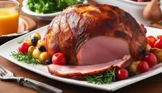 a ham on a white plate with fruit and vegetables around it, ready to be cooked