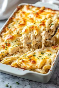 a spoon full of macaroni and cheese being lifted from a casserole dish