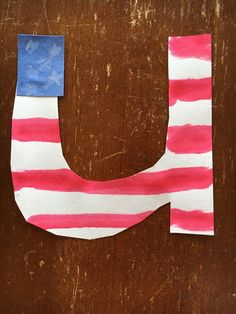 the letter u painted in red, white and blue stripes with a tape sticking out of it