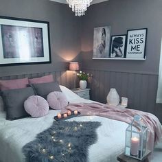 a bedroom decorated in grey and pink with pictures on the wall