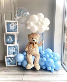 a teddy bear sitting on top of blue balloons